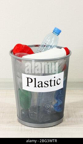 Assorted trash in bucket on room background Stock Photo