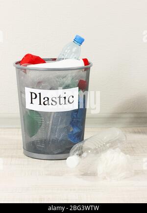 Assorted trash in bucket on room background Stock Photo