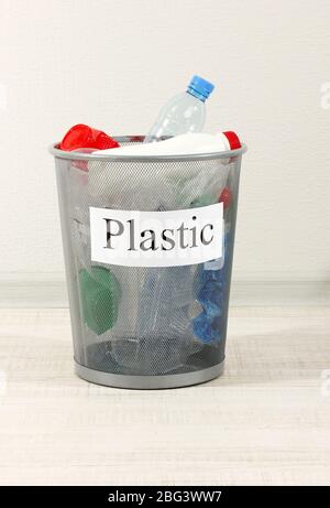 Assorted trash in bucket on room background Stock Photo