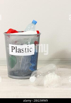 Assorted trash in bucket on room background Stock Photo