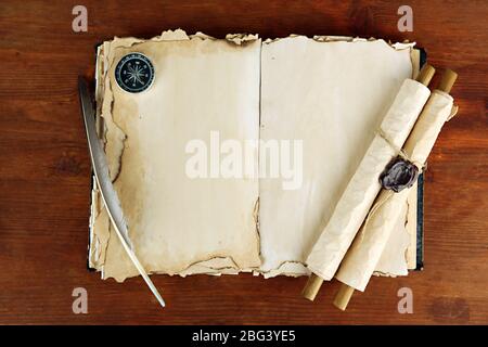 Open old book, scrolls and compass on wooden background Stock Photo