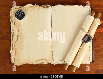 Open old book, scrolls and compass on wooden background Stock Photo