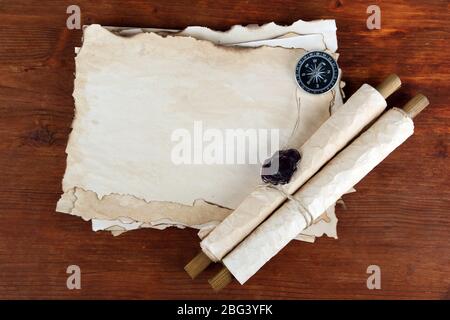 Old paper, scrolls and compass on wooden background Stock Photo