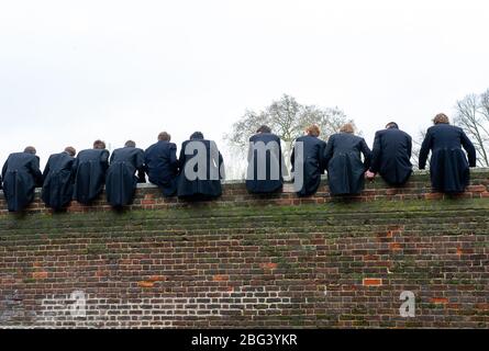 Eton, Windsor, Berkshire, UK.  20th November, 2010. Eton College boys sit on top of a high wall built in 1717 next to the Eton College playing fields as they watch their fellow schoolboys compete in The Wall Game. The first recorded Wall Game was in 1766. Eton College is a fee paying public school attended by many UK politicians including Boris Johnson and David Cameron. Prince William and Prince Harry also attended Eton College. Credit: Maureen McLean/Alamy Stock Photo