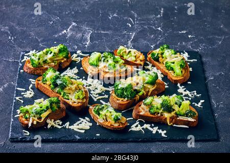Quick and easy healthy vegetarian broccoli melt sandwiches of blanched broccoli on a rye toasted bread with provolone cheese on top on a dark concrete Stock Photo