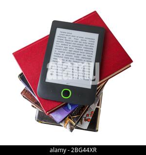 E-book reader on a stack of paper books isolated on white background. Copy space on e-book display. E-reading for pleasure and education. Top view. Stock Photo