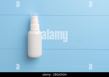 Alcohol spray disinfectant in a white plastic container on a blue wooden background. Disinfection of hands and objects. Copyspace. Stock Photo