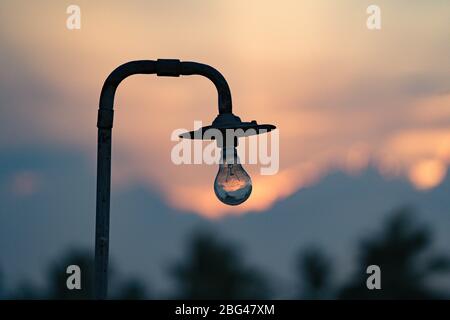 A vintage electric bulb with a beautiful sunset in the background Stock Photo