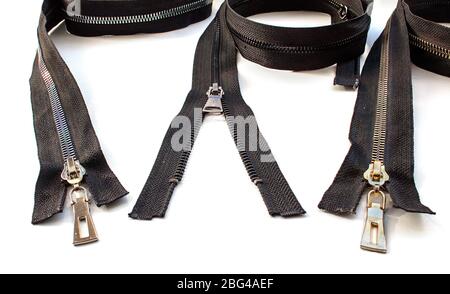 two closed and one opened metal  zippers closeup on white background Stock Photo