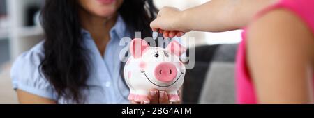 Girl throwing coin into moneybox Stock Photo