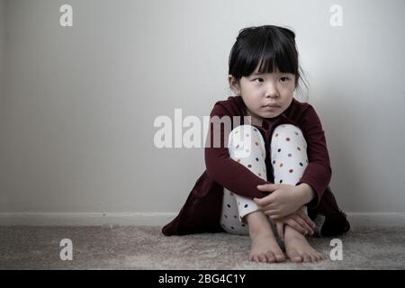 Lonely sad little girl holding her knees Stock Photo