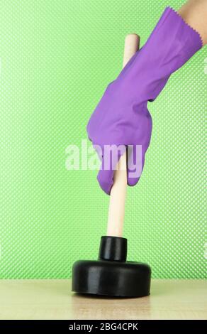 Toilet plunger in hand on green background Stock Photo
