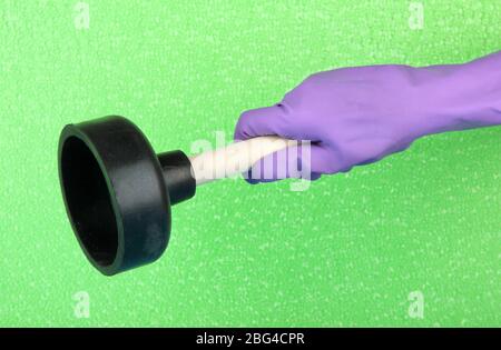 Toilet plunger in hand on green background Stock Photo