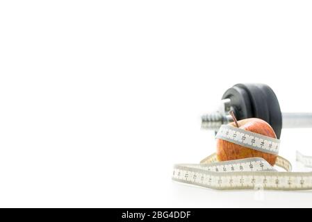 Close up of waist measuring tape wrapped around red apple on white background, part of black and silver dumbell visible in background. Stock Photo