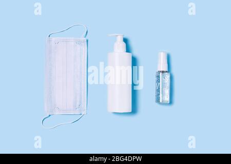 Flat lay with a medical mask placed in the center, a bottle of antiseptic soap and a hand sanitizer. Stock Photo