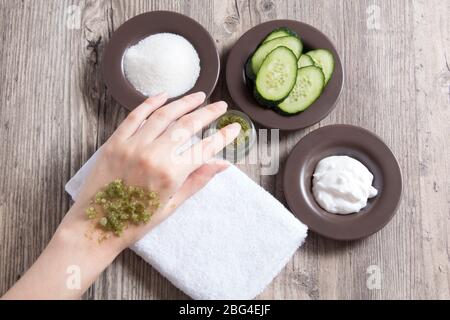 A woman applies a natural scrub to the body. Homemade scrub made of sugar, salt, cream and cucumber. Beauty, Spa, skin care, aromatherapy. Moisturizin Stock Photo