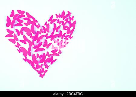 Paper butterflies in form of heart on wall Stock Photo