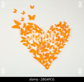 Paper orange butterfly in form of heart on wall Stock Photo