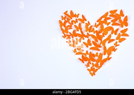 Paper butterflies in form of heart on wall Stock Photo