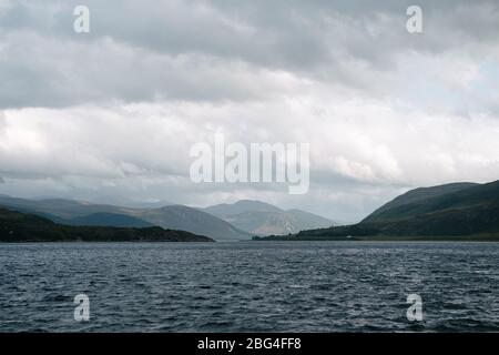 Looking east at dusk from Ullapool down Loch Broom towards the mountains with a stormy sky. Stock Photo