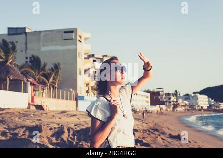 Young woman shading her eyes at beach at sunset Stock Photo