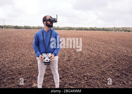 young man flies drone with glasses in the field Stock Photo