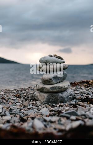 Small stack of stones or a cairn on the shore of Loch Broom in Ullapool in the West Highlands of Scotland. Stock Photo