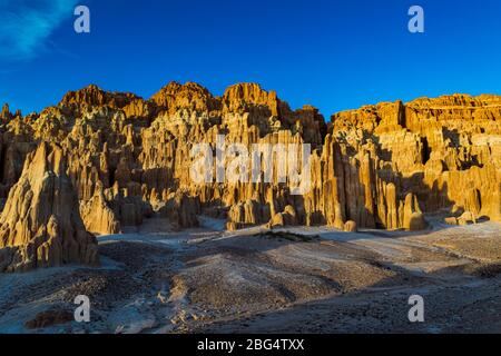 Golden sunlight covers the clay hills of Cathedral Gorge, Nevada against a clear blue sky Stock Photo