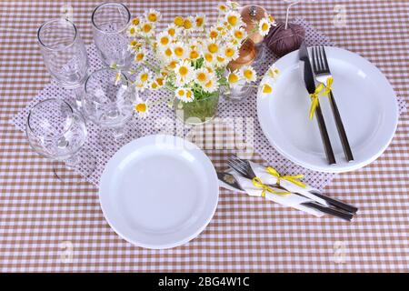 Table setting with chamomiles on checkered tablecloth Stock Photo