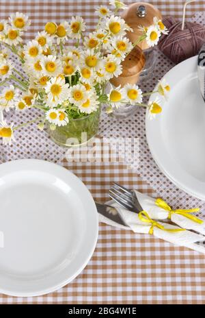 Table setting with chamomiles on checkered tablecloth Stock Photo