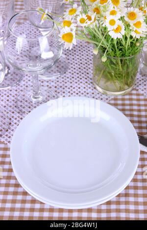 Table setting with chamomiles on checkered tablecloth Stock Photo