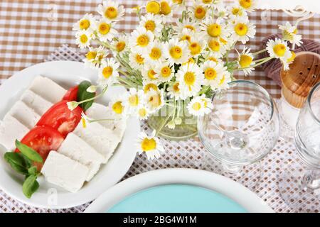 Table setting with chamomiles on checkered tablecloth Stock Photo