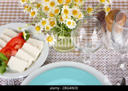 Table setting with chamomiles on checkered tablecloth Stock Photo