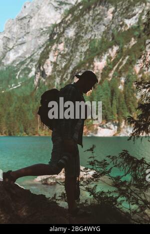 man climbing by rocks to shoot beautiful landscape of lake and mountains Stock Photo