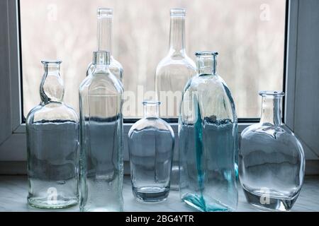 many empty drunk bottles on windowsill of home window Stock Photo
