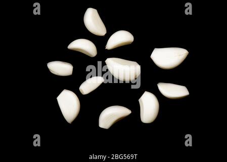 Some cloves of raw peeled garlic isolated on black background Stock Photo