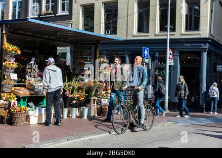 Amsterdam, Netherlands - September 7, 2018: Man on bicycle circulating and people walking in an old historic center of Amsterdam, Netherlands Stock Photo