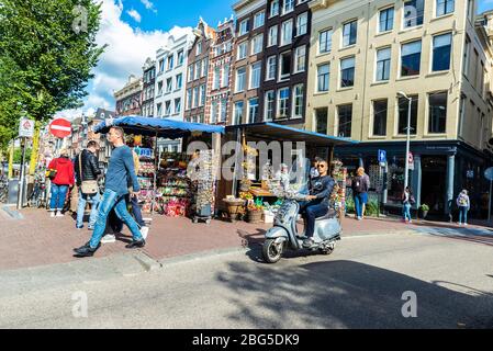 Amsterdam, Netherlands - September 7, 2018: Young man on motorbike circulating and people walking in an old historic center of Amsterdam, Netherlands Stock Photo