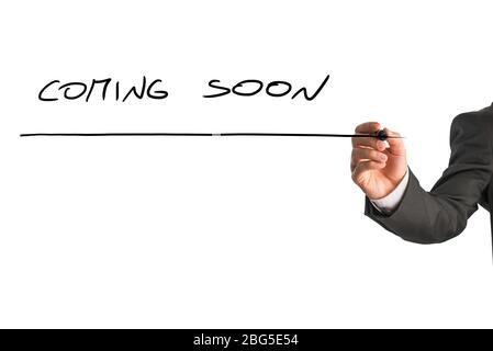 Hand of a man writing Coming soon on a virtual screen with a marker pen. Stock Photo