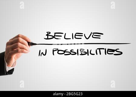 Closeup of male hand writing an inspirational message Believe in possibilities from behind a grey virtual screen, motivating you to never lose hope an Stock Photo