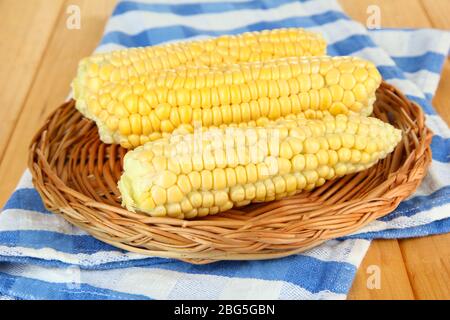 Fresh corn on wicker mat, on wooden background Stock Photo