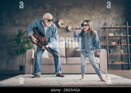 Photo of two people excited grandpa play guitar small granddaughter mic singing cool style trendy sun specs denim clothes repetition school concert Stock Photo