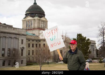 Helena, Montana - April 19, 2020: A senior citizen man protesting wearing a red Make America Great Again hat holding a sign saying to open up the gove Stock Photo