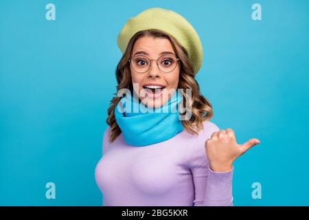 Portrait of astonished crazy girl indicate incredible promotion ads impressed point forefinger copyspace scream wow omg wear green headwear violet Stock Photo