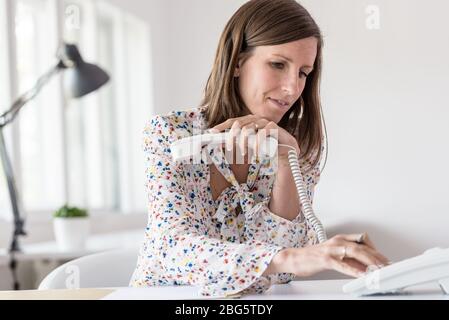 Young attractive woman smiling as she making a phone call conceptual of a call center or business communication. Stock Photo