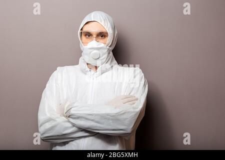 Doctor in biological hazard, protective medical suit, medical mask FFP3, goggles crossed arms over chest. Doctor in chemical protection clothing on Stock Photo