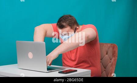 Funny frames of male using laptop. man working on a computer in a protective medical mask pretending to be a hacker. Stock Photo