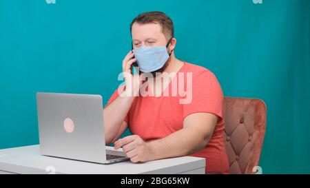 Man working from home. Using a smartphone. Bearded man in a protective mask works at home. Stock Photo