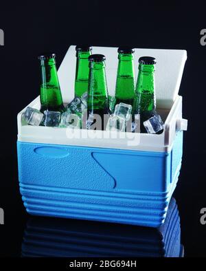 Bottles of beer with ice cubes in mini refrigerator, on black background Stock Photo
