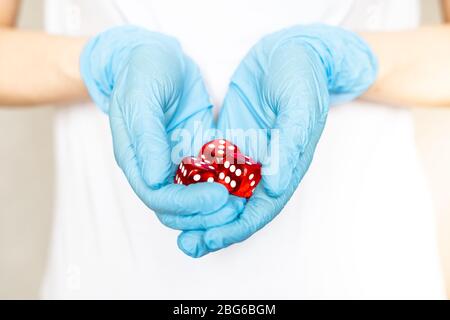 Woman holding red dices in hands with rubber gloves Stock Photo